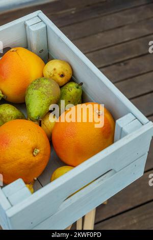 una scatola di legno blu piena di pompelmi, pere di vario genere Foto Stock