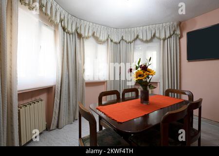 Soggiorno di una casa con angolo dedicato ad una sala da pranzo con tavolo in legno e sei sedie abbinate in una sala semicircolare Foto Stock