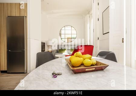 Soggiorno con tavolo da pranzo in marmo bianco circondato da sedie in resina grigia Foto Stock