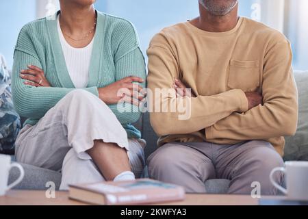 Arrabbiato, sconvolto e infastidito con una coppia di braccia seduta incrociate su un divano nel soggiorno della loro casa. Litigando, discordanza e rabbia con un uomo e. Foto Stock