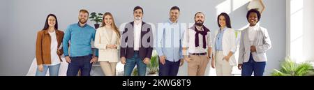 Diversi uomini d'affari felici in fila vicino al muro sorridente guardando la fotocamera, personale internazionale ritratto di successo, concetto di risorse umane Foto Stock