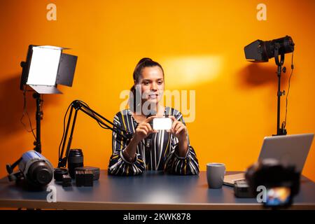 Influencer che parla di mini LED che può essere utilizzato anche in studio. Video blogger registrazione di un vlog con tecnologia di prodotto attrezzature utilizzate in videografia e fotografia. Foto Stock