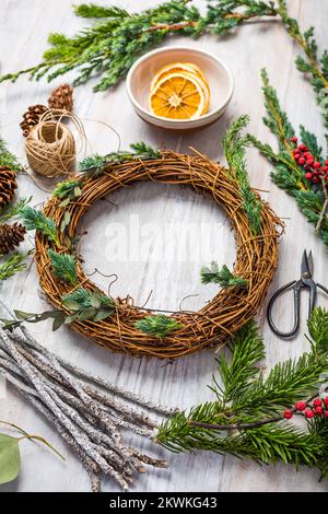 Passi di fare wreath della porta di natale, vista dall'alto verso il basso del tavolo da lavoro del fiorista Foto Stock