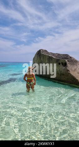 Donne asiatiche che si adagiano sulla spiaggia bianca tropicale con l'oceano color turqouse delle Isole Similan Thailandia. Foto Stock