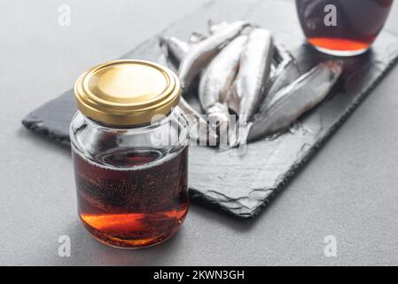 Il garum è una salsa di pesce fermentata. Preparato per fermentazione a base di pesce, salsa al garum salato in bottiglia su fondo grigio. Garum salsa di pesce fatta da Foto Stock