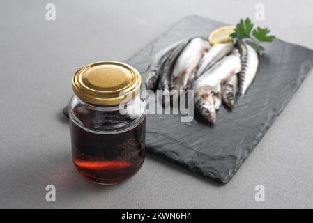 Il garum è una salsa di pesce fermentata. Preparato per fermentazione a base di pesce, salsa al garum salato in bottiglia su fondo grigio. Garum salsa di pesce fatta da Foto Stock