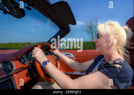 Donna bionda alla guida di un'auto sportiva Porsche nel Regno Unito. Foto Stock