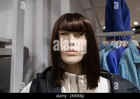 Primo piano di un manichino di una donna con una parrucca in un centro commerciale con vestiti Foto Stock