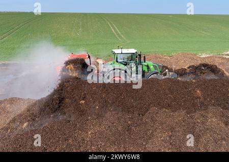 Girando un mucchio di concime sopra fare composto per spargere su terreno agricolo, che aiuta ad aumentare la qualità del suolo. North Yorkshire, Regno Unito. Foto Stock