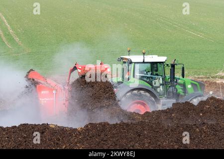 Girando un mucchio di concime sopra fare composto per spargere su terreno agricolo, che aiuta ad aumentare la qualità del suolo. North Yorkshire, Regno Unito. Foto Stock