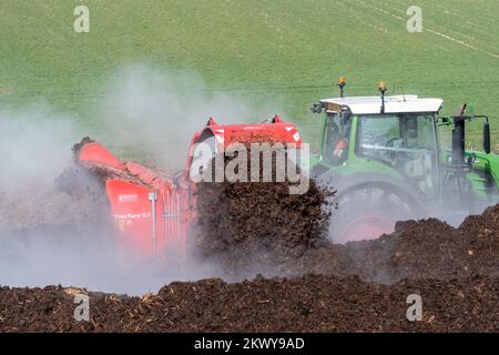 Girando un mucchio di concime sopra fare composto per spargere su terreno agricolo, che aiuta ad aumentare la qualità del suolo. North Yorkshire, Regno Unito. Foto Stock