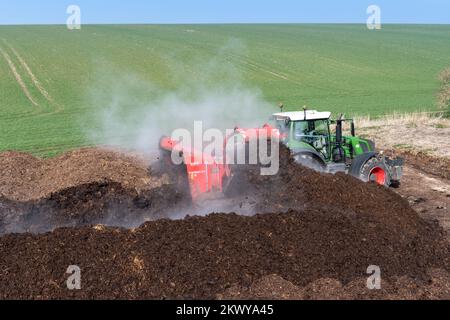 Girando un mucchio di concime sopra fare composto per spargere su terreno agricolo, che aiuta ad aumentare la qualità del suolo. North Yorkshire, Regno Unito. Foto Stock