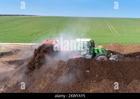 Girando un mucchio di concime sopra fare composto per spargere su terreno agricolo, che aiuta ad aumentare la qualità del suolo. North Yorkshire, Regno Unito. Foto Stock