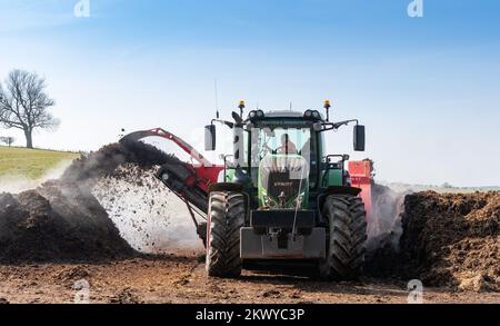 Girando un mucchio di concime sopra fare composto per spargere su terreno agricolo, che aiuta ad aumentare la qualità del suolo. North Yorkshire, Regno Unito. Foto Stock