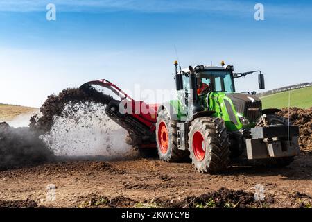 Girando un mucchio di concime sopra fare composto per spargere su terreno agricolo, che aiuta ad aumentare la qualità del suolo. North Yorkshire, Regno Unito. Foto Stock