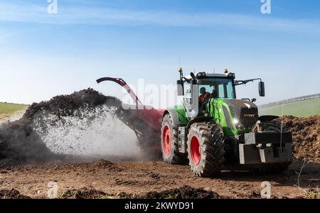 Girando un mucchio di concime sopra fare composto per spargere su terreno agricolo, che aiuta ad aumentare la qualità del suolo. North Yorkshire, Regno Unito. Foto Stock