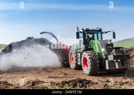 Girando un mucchio di concime sopra fare composto per spargere su terreno agricolo, che aiuta ad aumentare la qualità del suolo. North Yorkshire, Regno Unito. Foto Stock