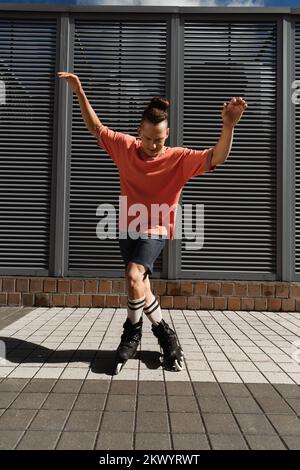 Skater roller facendo trucco alla luce del sole su strada urbana, immagine stock Foto Stock