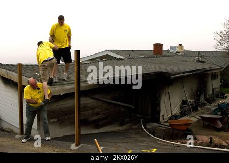 Wild Fires, Malibu, CA, 16th novembre 2007 Presidente Blackburn, E gli anziani Smith e Tuggle della Chiesa Mormonica di Los Angeles si arrampicano su questa casa per aiutare a ripulire e rimuovere i detriti dalla casa dei membri della Chiesa Don Konold e della moglie Annemarie. Le loro case erano una delle poche case danneggiate dal fuoco del canyon di Malibu. Fotografie relative a disastri e programmi, attività e funzionari di gestione delle emergenze Foto Stock