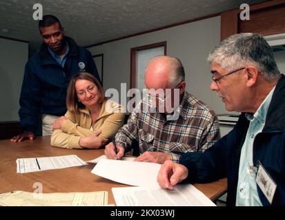 Incendi boschivi, Delzura, CA, 8 dicembre 2007 Kenneth Tingman, Operazioni assistente speciale per FEMA, a sinistra, e Louis Narciso, operazioni dirette di edilizia residenziale FEMA, a destra, guardare come Jon Grice firma un accordo di occupazione che consente a lui e sua moglie Leighann, centro, di occupare temporaneamente la casa mobile in cui sono seduti. La coppia ha perso la loro casa e molti possedimenti domestici quando i fuochi selvatici hanno bruciato la loro comunità in ottobre. Amanda Bicknell/FEMA.. Fotografie relative a disastri e programmi, attività e funzionari di gestione delle emergenze Foto Stock