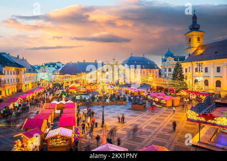 Sibiu, Romania - Dicembre 2014: Immagine notturna con i turisti al mercato di Natale di Sibiu in Piazza Grande, centro medievale della Transilvania. Foto Stock