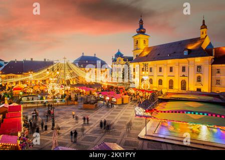 Sibiu, Romania - Dicembre 2014: Immagine notturna con i turisti al mercato di Natale di Sibiu in Piazza Grande, centro medievale della Transilvania. Foto Stock