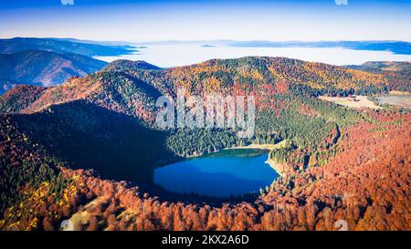 Lago di Sant'Ana, Transilvania, Romania. Splendido paesaggio autunnale con foresta colorata e idilliaco lago vulcanico un popolare turistico e destinazione di viaggio Foto Stock