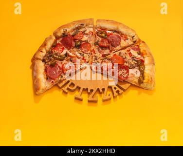 Pizza italiana con pomodori e formaggio su un vassoio di legno su sfondo giallo colorato Foto Stock