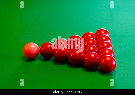 Palline da biliardo rosse e rosa allestite per giocare su un tavolo da biliardo baize verde Foto Stock