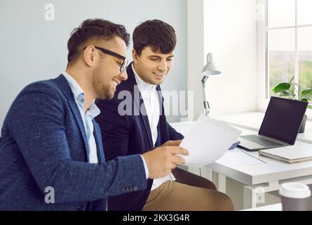 Due giovani uomini d'affari felici che fanno la documentazione professionale nell'ufficio dell'azienda Foto Stock