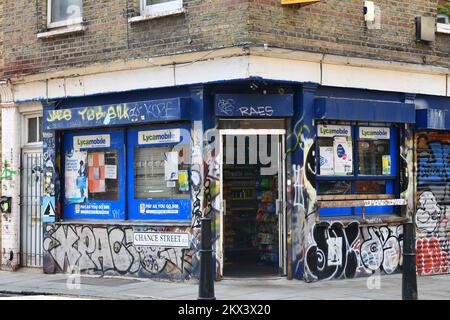 Negozio d'angolo coperto da graffiti all'incrocio tra Chance Street e Old Nichol Street a Shoreditch London Foto Stock