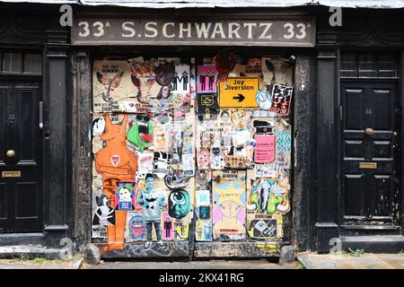 S. Schwartz vecchio cortile cancelli con poster e graffiti al 33A Fournier St, Londra E1 6QE Foto Stock