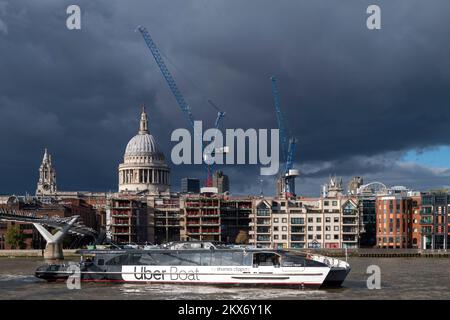 Una Uber Boat presso Thames Clippers, autobus fluviale che arriva sotto il ponte Millennium prima di attraccare al bankside Pier, St La Cattedrale di Pau può essere vista nella Foto Stock