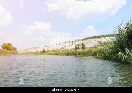 Antiche montagne di gesso multimillion sulla superficie della steppa della terra. Montagne di gesso bianco in paesaggio con fiume e alberi verdi Foto Stock