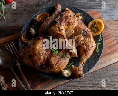 Cosce di pollo arrosto con limone, timo e aglio su tavolo di legno Foto Stock