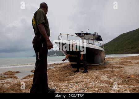 Uragano di allagamento/tempesta tropicale - St. Thomas, Isole Vergini statunitensi, 31 agosto 2010, ufficiali del Dipartimento di polizia delle risorse naturali (DPNR) Evans Jackson (L) e Andrea Tromben (R) che ispezionano una barca che ha rotto la sua linea di ormeggio ed è stato colpito in alto e a secco dai potenti venti di Hurricane Earl. Andrea Booher/FEMA.. Fotografie relative a disastri e programmi, attività e funzionari di gestione delle emergenze Foto Stock