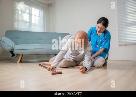 Anziano disabile paziente con bastone calato sul pavimento e giovane assistente attento Foto Stock