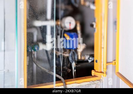 un tubo dell'acqua in primo piano e un contatore dell'acqua sullo sfondo sfocato Foto Stock