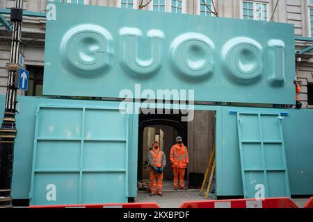 I lavoratori controllano le distanze mentre il logo Gucci è posizionato sopra la facciata del nuovo negozio di punta di Bond Street durante un periodo di costruzione e ristrutturazione, il 29th novembre 2022, a Londra, Inghilterra. Foto Stock