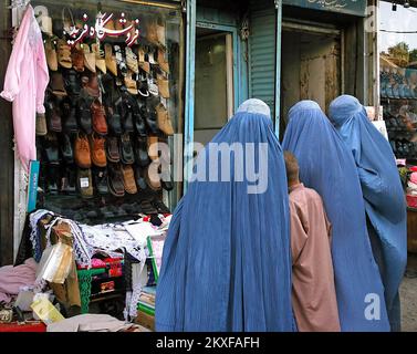 Kabul / Afghanistan: Donne afghane in piedi al di fuori di un negozio di scarpe a Kabul, Afghanistan indossando burqa blu. Foto Stock