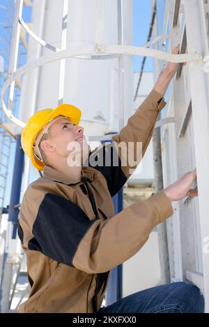 un operaio che sale scala in metallo Foto Stock