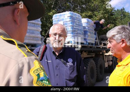 Uragano alluvione/tempesta tropicale - Ludlow, Vt. , 30 agosto 2011 l'amministratore della FEMA W. Craig Fugate Center, discute l'istituto a Ludlow con lo Sgt. Tom Williams della polizia di Stato del Vermont ha lasciato, mentre il direttore della gestione di emergenza, Ron Bixby destra, ascolta. I lavoratori scaricano l'acqua in bottiglia sullo sfondo. Il Vermont è stato colpito da un'inondazione lampo a seguito della tempesta tropicale Irene. Vermont Tropical Storm Irene. Fotografie relative a disastri e programmi, attività e funzionari di gestione delle emergenze Foto Stock