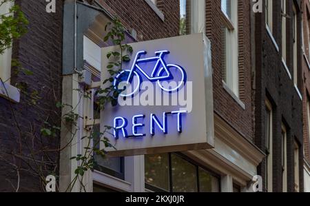 Una foto di un neon noleggio bici segno ad Amsterdam. Foto Stock