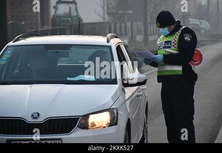 La polizia sui posti di controllo tra la contea di Brod-Posavina e la contea di Pozega-Slavonia controlla il pass di viaggio, a Blice, in Croazia, il 23 dicembre 2020. Da oggi è vietato lasciare la contea in cui la persona ha una residenza permanente o temporanea. Ciò non si applica al personale necessario per la manutenzione del traffico, alla migrazione quotidiana dei dipendenti nei servizi sanitari, alla consegna di farmacia, alle utenze, alla fornitura di gas ed elettricità, ai servizi di sicurezza, ai giornalisti, ai pazienti, ai viaggi da e per il lavoro, ai servizi di emergenza per prevenire la diffusione delle malattie e al personale diplomatico. Il divieto di viaggio entra in per Foto Stock