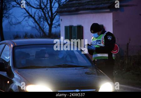 La polizia sui posti di controllo tra la contea di Brod-Posavina e la contea di Pozega-Slavonia controlla il pass di viaggio, a Blice, in Croazia, il 23 dicembre 2020. Da oggi è vietato lasciare la contea in cui la persona ha una residenza permanente o temporanea. Ciò non si applica al personale necessario per la manutenzione del traffico, alla migrazione quotidiana dei dipendenti nei servizi sanitari, alla consegna di farmacia, alle utenze, alla fornitura di gas ed elettricità, ai servizi di sicurezza, ai giornalisti, ai pazienti, ai viaggi da e per il lavoro, ai servizi di emergenza per prevenire la diffusione delle malattie e al personale diplomatico. Il divieto di viaggio entra in per Foto Stock