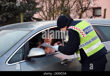 La polizia sui posti di controllo tra la contea di Brod-Posavina e la contea di Pozega-Slavonia controlla il pass di viaggio, a Blice, in Croazia, il 23 dicembre 2020. Da oggi è vietato lasciare la contea in cui la persona ha una residenza permanente o temporanea. Ciò non si applica al personale necessario per la manutenzione del traffico, alla migrazione quotidiana dei dipendenti nei servizi sanitari, alla consegna di farmacia, alle utenze, alla fornitura di gas ed elettricità, ai servizi di sicurezza, ai giornalisti, ai pazienti, ai viaggi da e per il lavoro, ai servizi di emergenza per prevenire la diffusione delle malattie e al personale diplomatico. Il divieto di viaggio entra in per Foto Stock