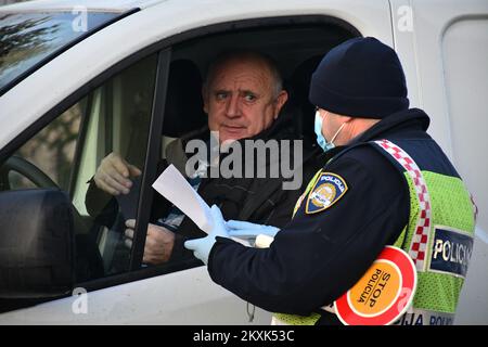 La polizia sui posti di controllo tra la contea di Brod-Posavina e la contea di Pozega-Slavonia controlla il pass di viaggio, a Blice, in Croazia, il 23 dicembre 2020. Da oggi è vietato lasciare la contea in cui la persona ha una residenza permanente o temporanea. Ciò non si applica al personale necessario per la manutenzione del traffico, alla migrazione quotidiana dei dipendenti nei servizi sanitari, alla consegna di farmacia, alle utenze, alla fornitura di gas ed elettricità, ai servizi di sicurezza, ai giornalisti, ai pazienti, ai viaggi da e per il lavoro, ai servizi di emergenza per prevenire la diffusione delle malattie e al personale diplomatico. Il divieto di viaggio entra in per Foto Stock