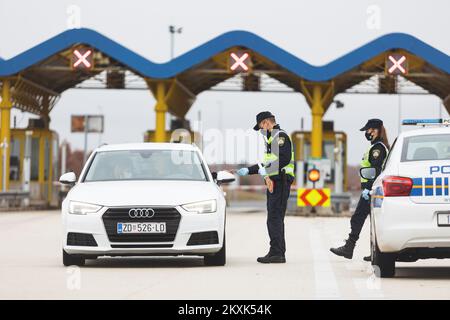 La polizia sui posti di controllo all'entrata dell'autostrada nella contea di Zara controlla il pass di viaggio, a Zara, Croazia, il 23 dicembre 2020. Da oggi è vietato lasciare la contea in cui la persona ha una residenza permanente o temporanea. Ciò non si applica al personale necessario per la manutenzione del traffico, alla migrazione quotidiana dei dipendenti nei servizi sanitari, alla consegna di farmacia, alle utenze, alla fornitura di gas ed elettricità, ai servizi di sicurezza, ai giornalisti, ai pazienti, ai viaggi da e per il lavoro, ai servizi di emergenza per prevenire la diffusione delle malattie e al personale diplomatico. Il divieto di viaggio entra in vigore il dicembre Foto Stock