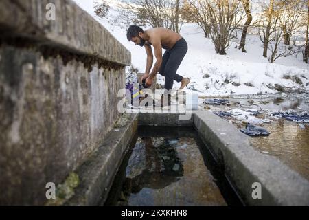 Un migrante dal Pakistan Hagiaz Abdulrehman si pulisce in un flusso nel campo migrante Lipa, vicino Bihac, Bosnia-Erzegovina, il 15 gennaio 2021. L'acqua nei serbatoi si è congelata questa mattina perché la temperatura alle ore 9 era di -14 gradi Celsius. Il Camp Lipa sarà completamente funzionale in 3 mesi. Foto: Armin Durgut/PIXSELL Foto Stock