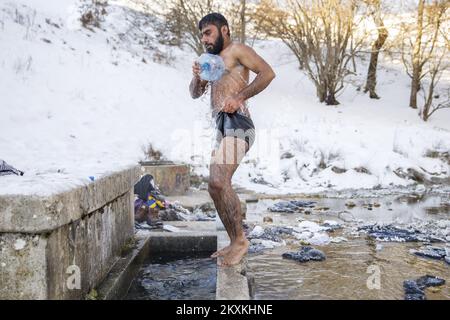 Un migrante dal Pakistan Hagiaz Abdulrehman si pulisce in un flusso nel campo migrante Lipa, vicino Bihac, Bosnia-Erzegovina, il 15 gennaio 2021. L'acqua nei serbatoi si è congelata questa mattina perché la temperatura alle ore 9 era di -14 gradi Celsius. Il Camp Lipa sarà completamente funzionale in 3 mesi. Foto: Armin Durgut/PIXSELL Foto Stock